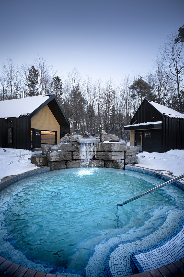 Vetta Nordic Spa circular pool surrounded by a blanket of snow with Finnish inspired buildings in the background