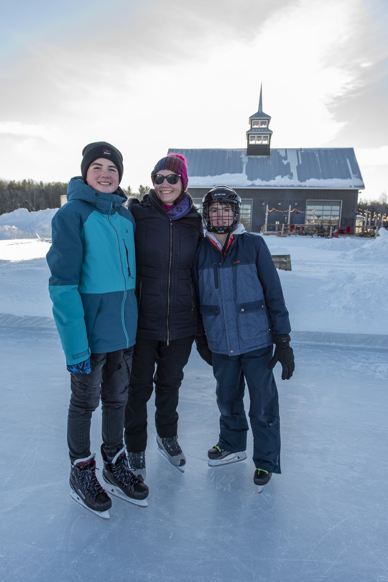 Quayle's Brewery mom and two boys pose smiling on outdoor skating rink in front of the brewery