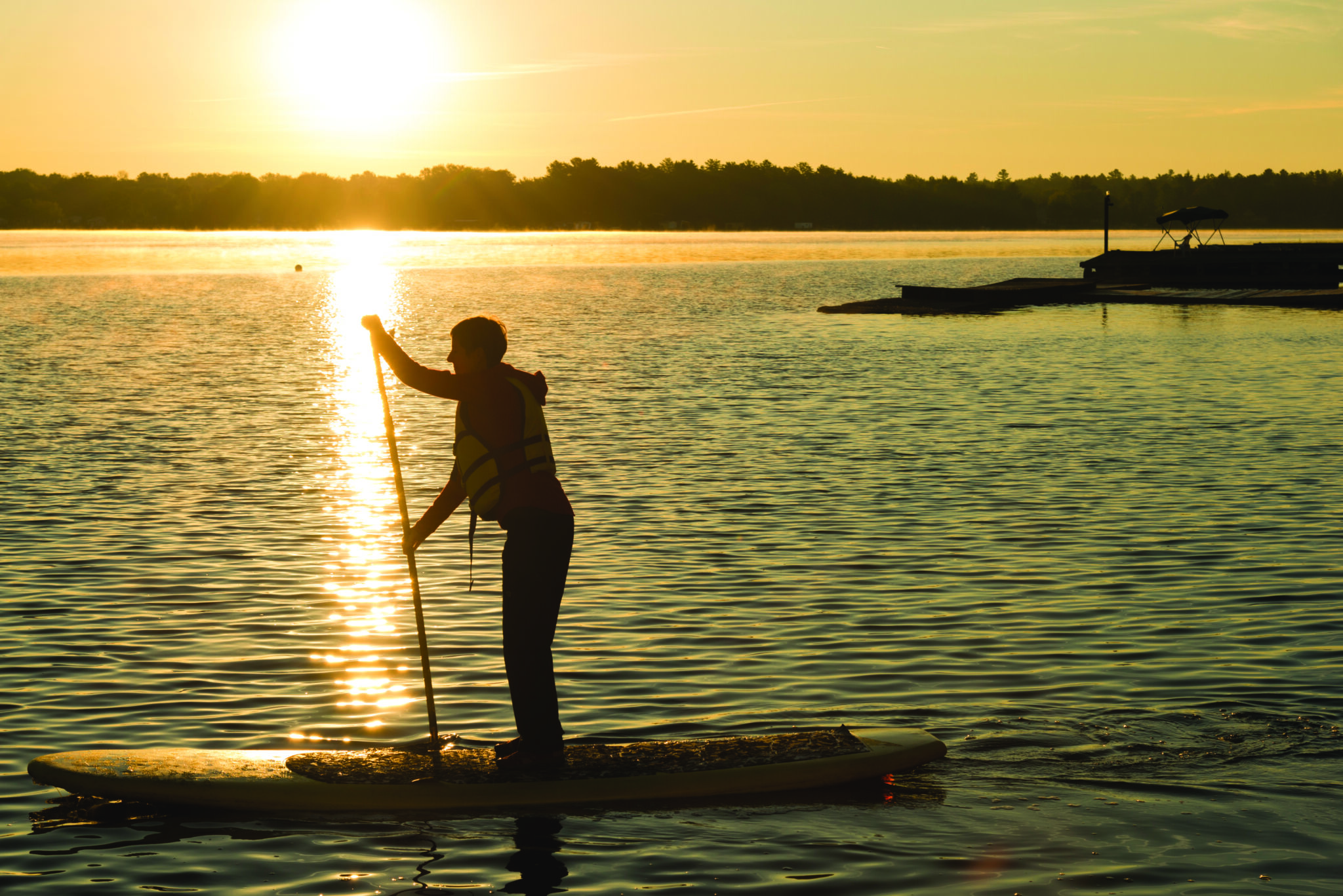 Man paddle boarding at sunset