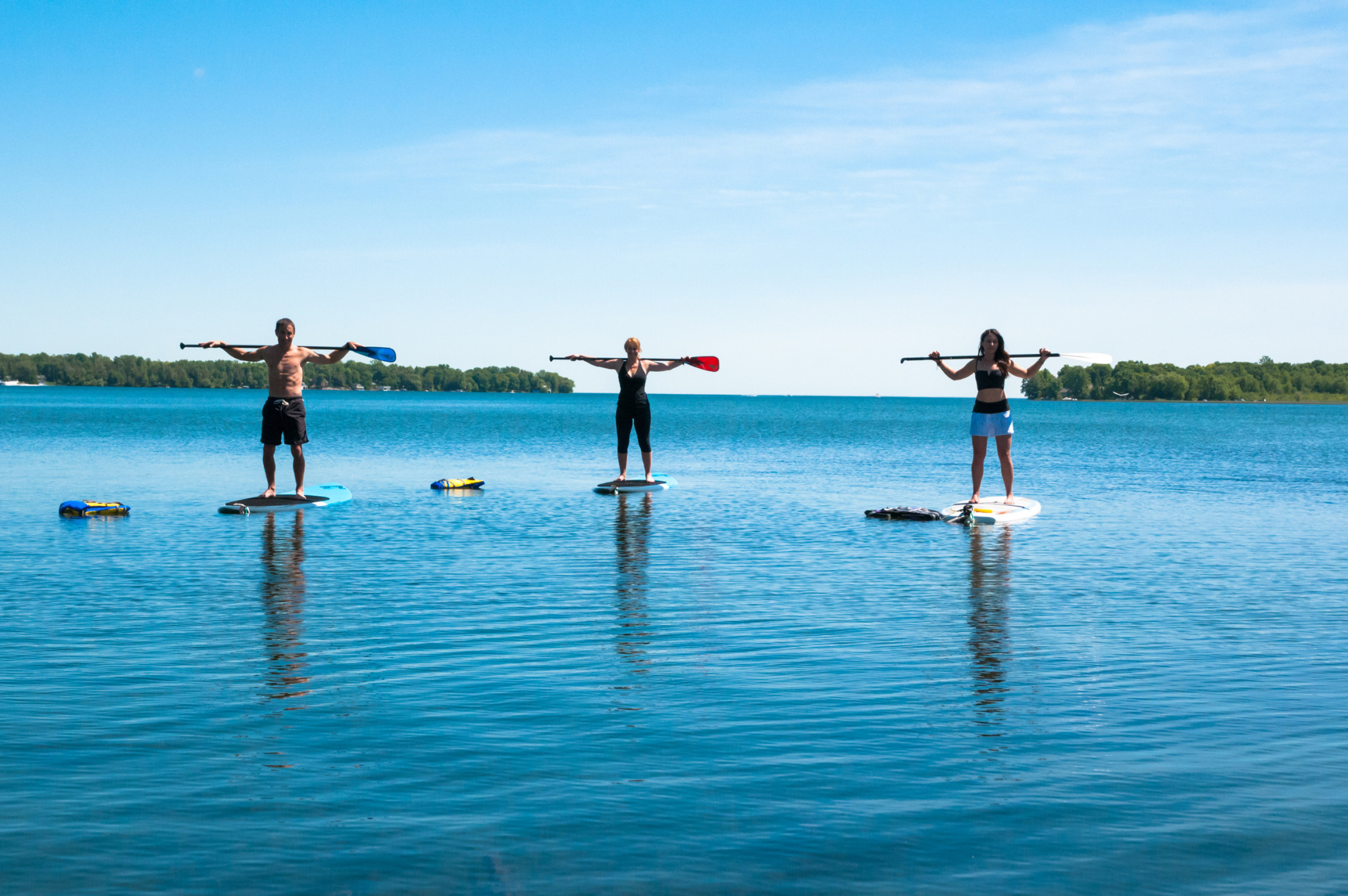 Three friends paddle boarding on Lake Couchiching
